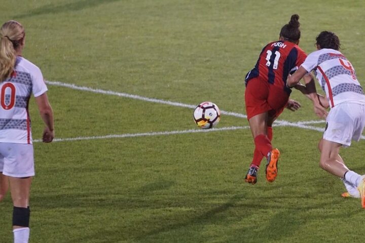 Photo taken during female league football match. Two women fighting for a ball followed by another defender.