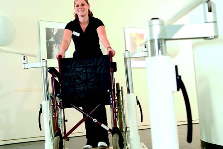 photo of therapist pushing wheelchair along walking rails for rehab