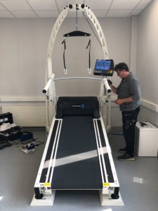 man tightening bolts on treadmill