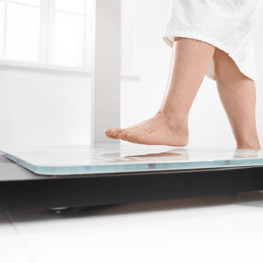 Patient stepping onto weighing scale for Bioelectrical Impedance Analysis (BIA)